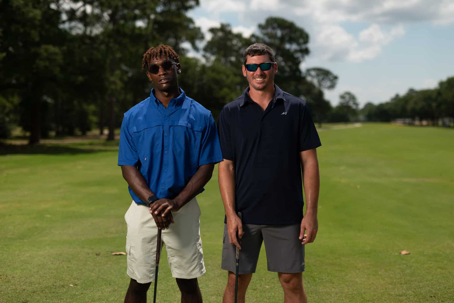 Two men on golf course holding golf clubs and wearing MSC shorts