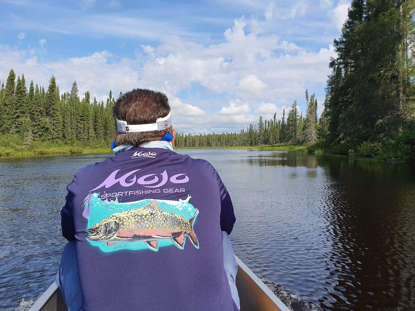Man leaning forward in small boat wearing Mojo Sportfishing Gear performance shirt in dark blue